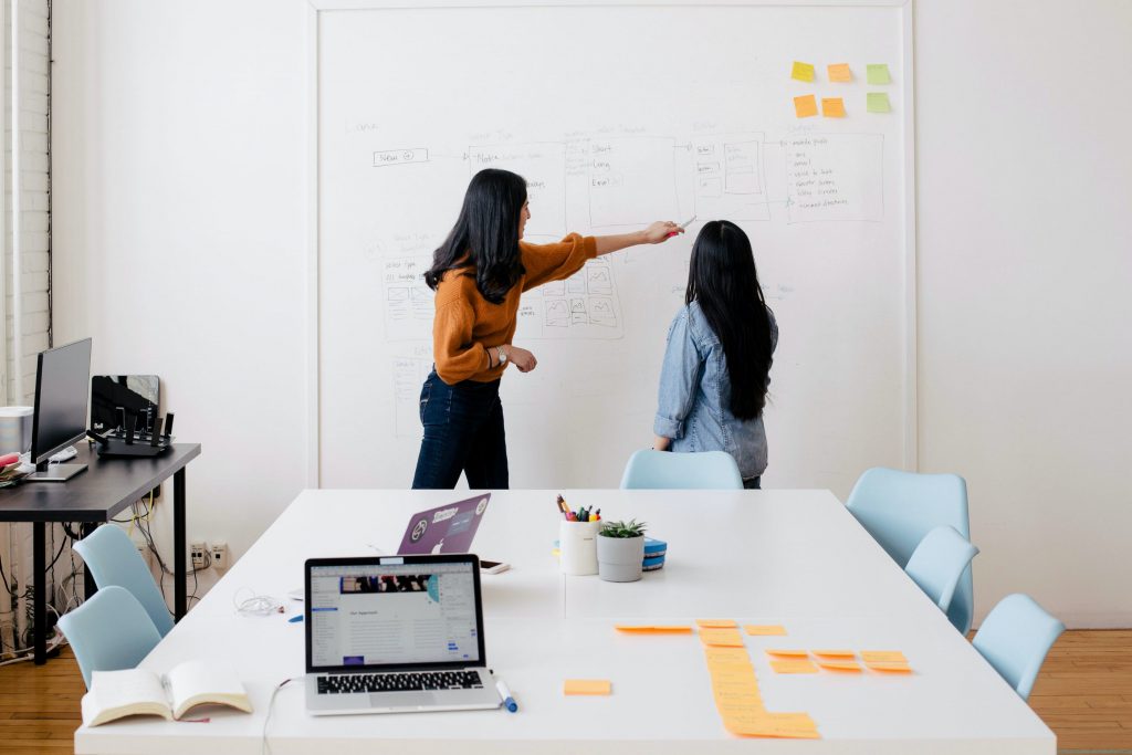 image of woman pointing to white board