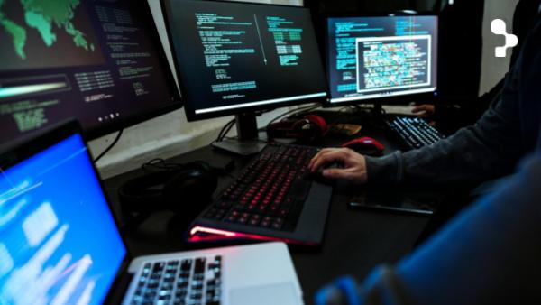 Illustrative image of engineers monitoring software quality and production risk across complex systems. A developer at a dark desk types on a backlit keyboard surrounded by multiple monitors and a laptop showing code, a header visual for the article Why Production Bugs Still Reach Users in Complex Engineering Teams